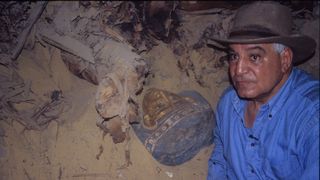 Egyptologist Zahi Hawass poses next to a mummy.
